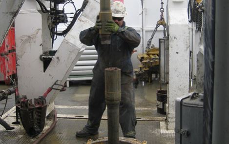 roughneck stabbing pipe on the rig floor