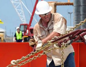 a roustabout tightening a chain boomer