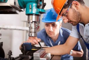 supervisor and worker checking the measurements on a piece of equipment